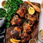 Crispy dry rub chicken thighs with homemade lemon pepper rub on a sheet pan with lemon wedges and parsley