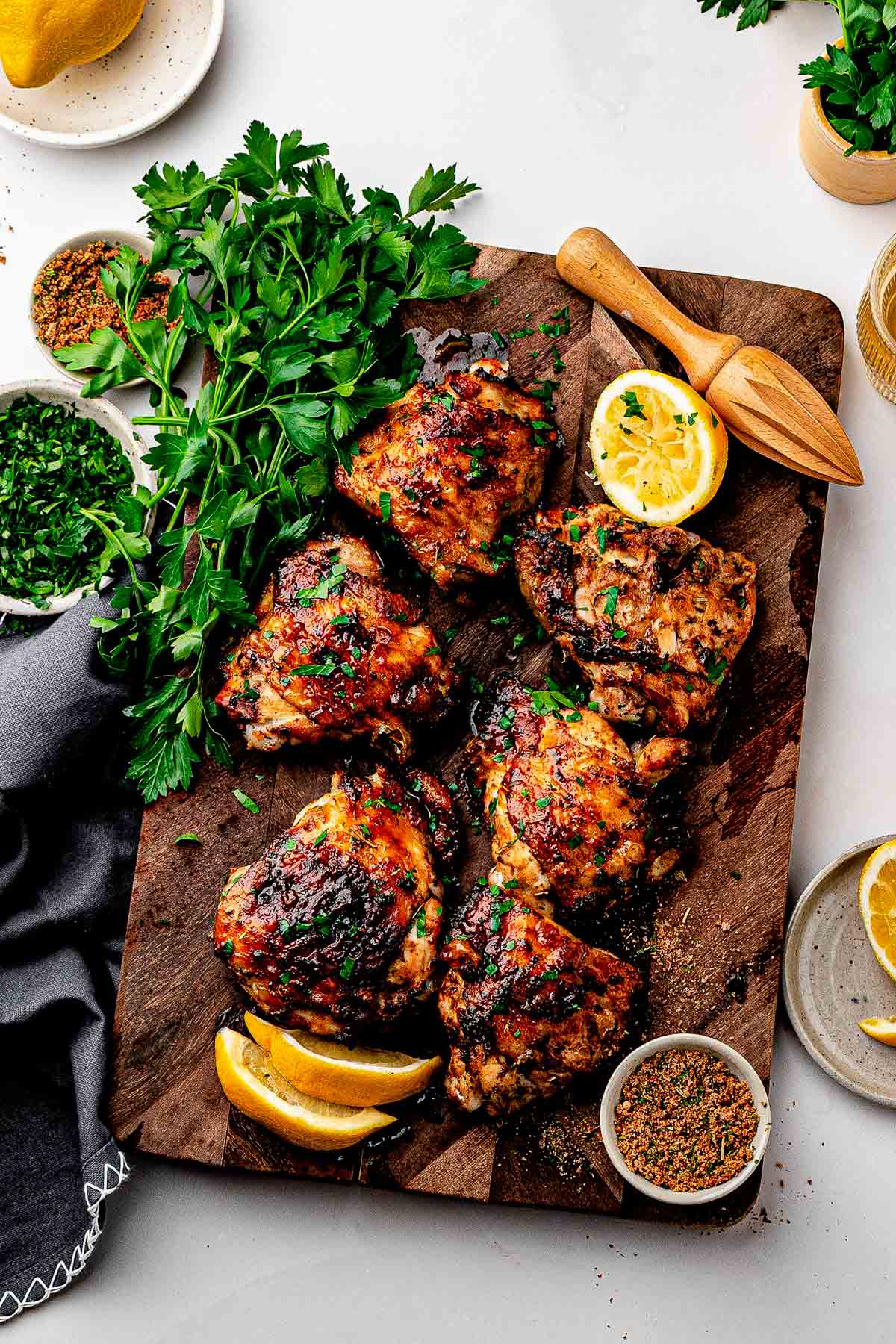 Crispy dry rub chicken thighs with homemade lemon pepper rub on a sheet pan with lemon wedges and parsley