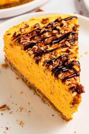 A slice of creamy no-bake pumpkin cheesecake with crust and pecans