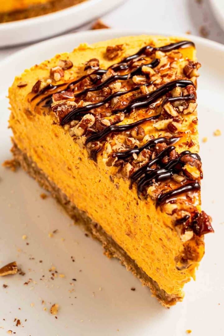 A slice of creamy no-bake pumpkin cheesecake with crust and pecans