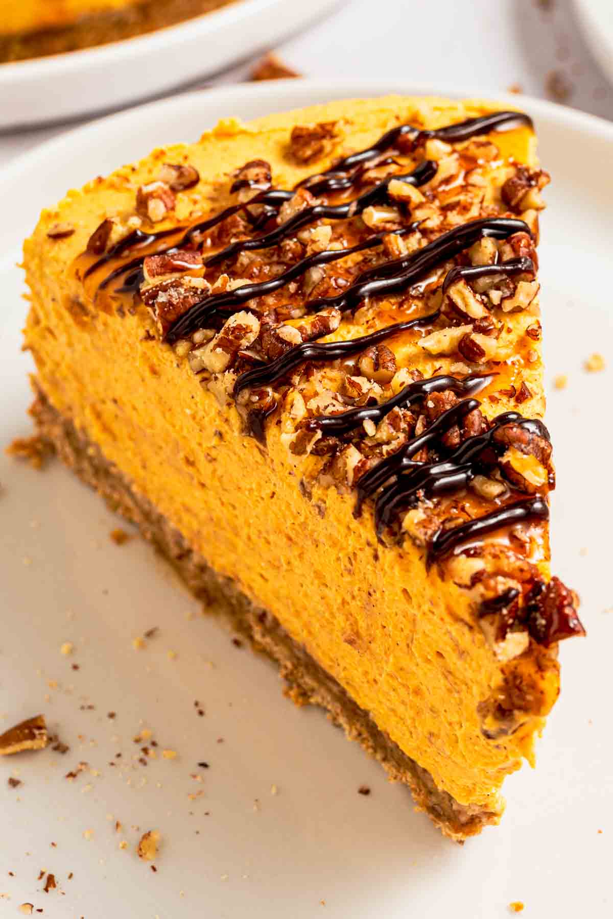 A slice of creamy no-bake pumpkin cheesecake with crust and pecans
