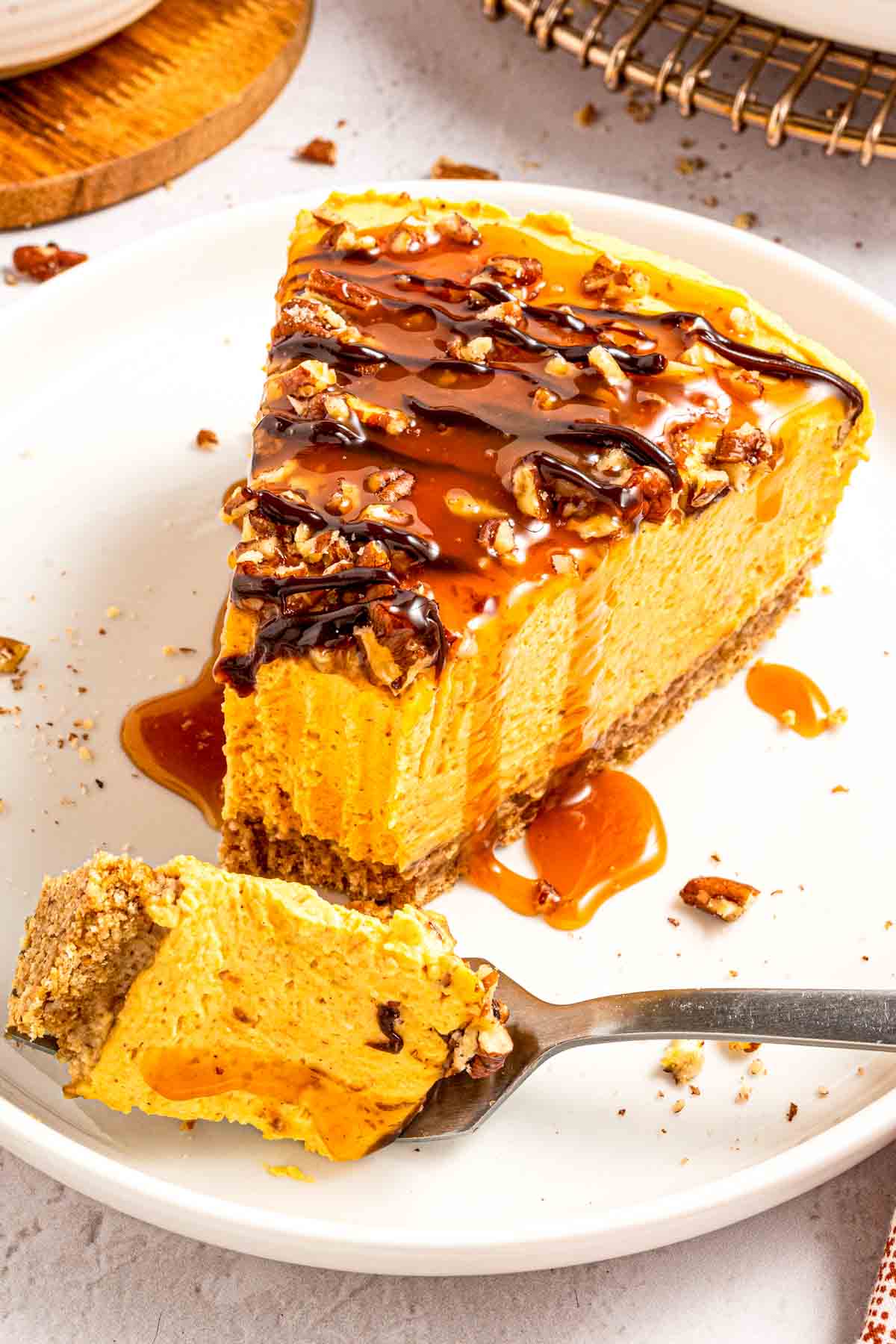 Fork lifting a bite of creamy no-bake pumpkin cheesecake with crust and pecans