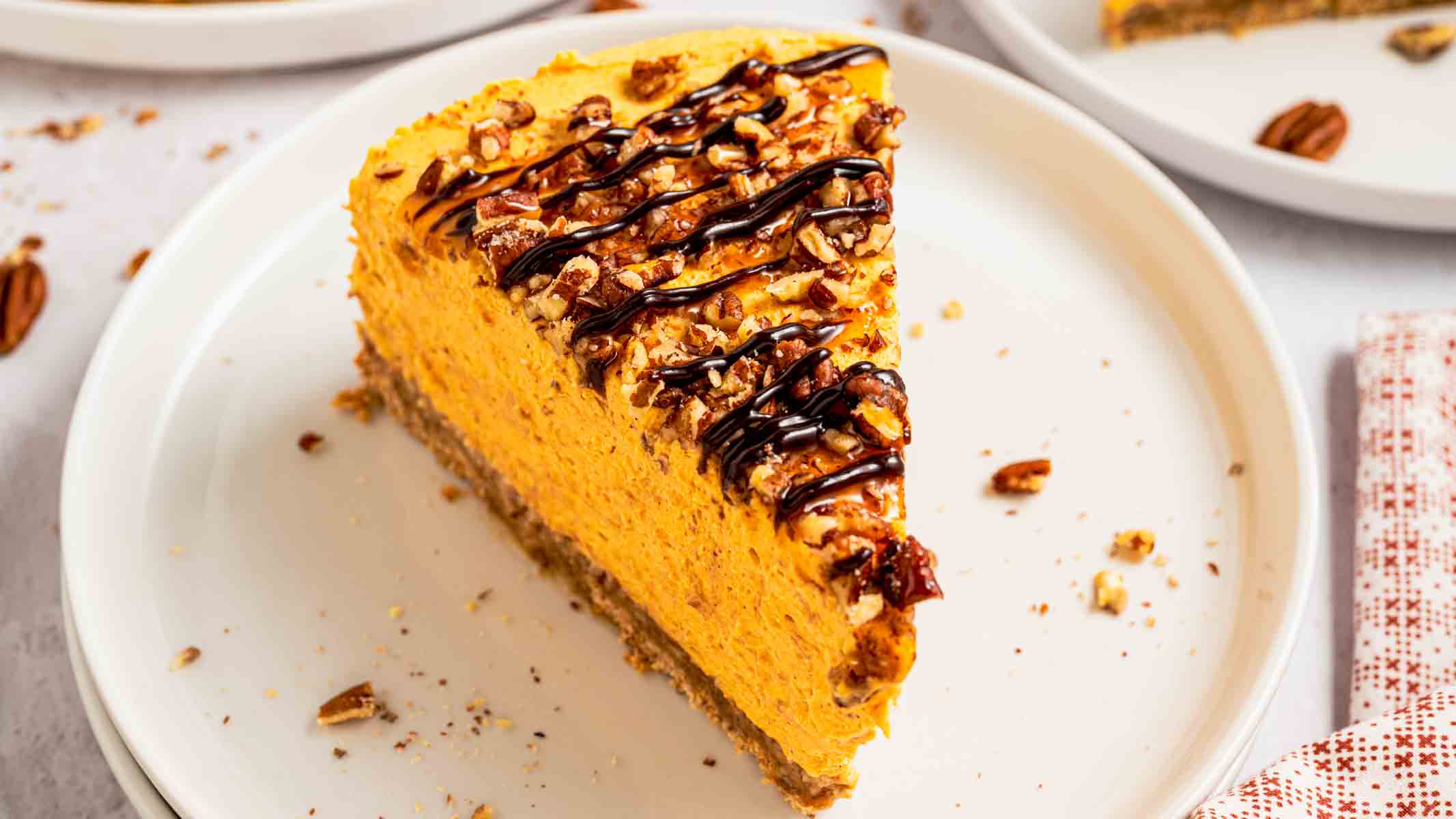 Clean slice of no bake pumpkin turtle cheesecake on a plate showing the pecan graham crust and creamy filling