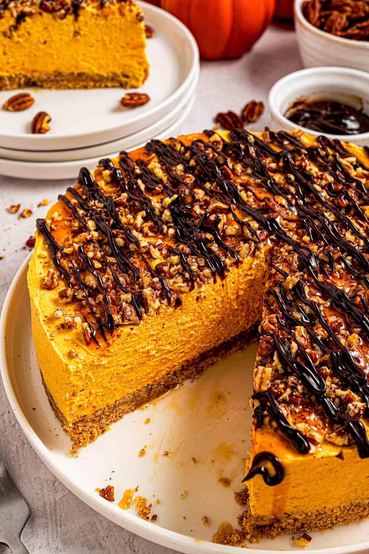 Sprinkling chopped pecans over the top of a no-bake pumpkin cheesecake