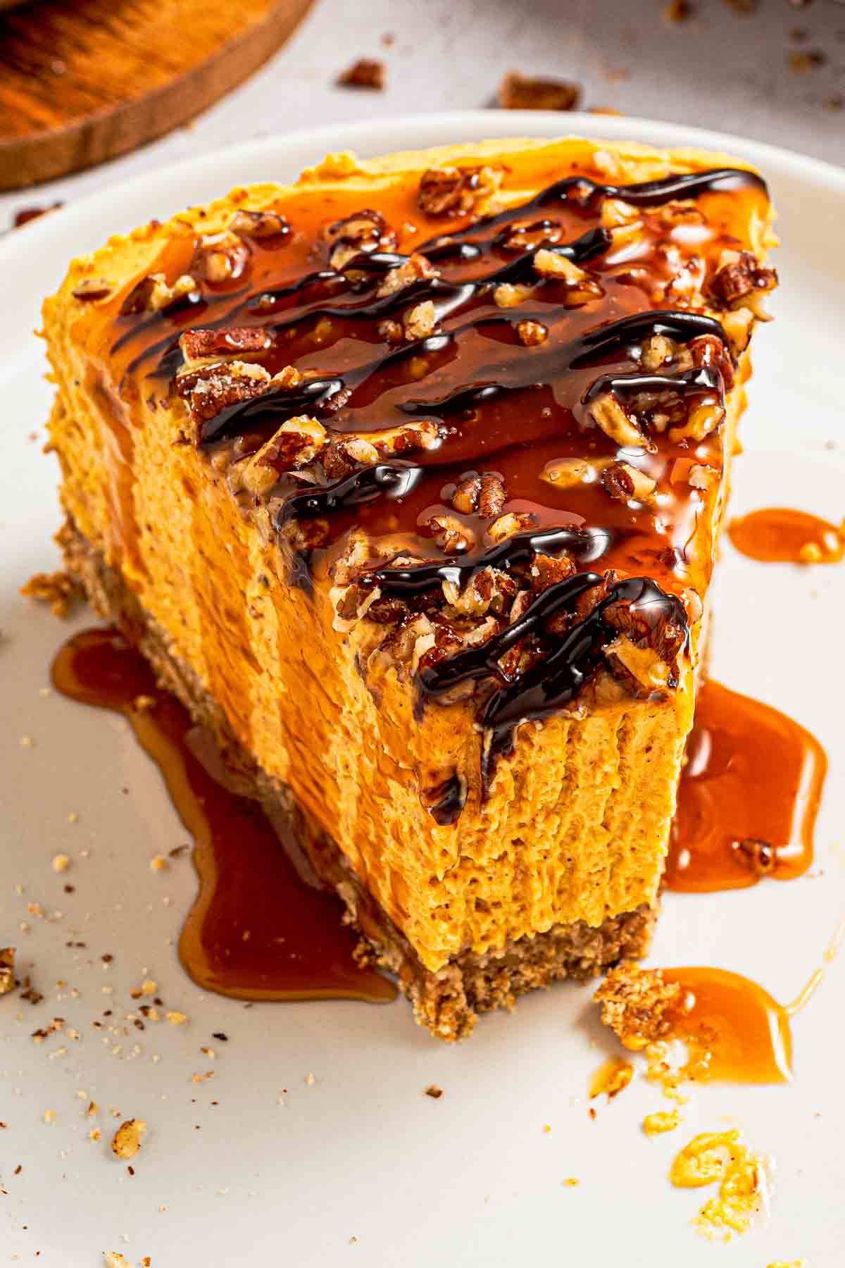 Fork lifting a bite of creamy no-bake pumpkin cheesecake with crust and pecans