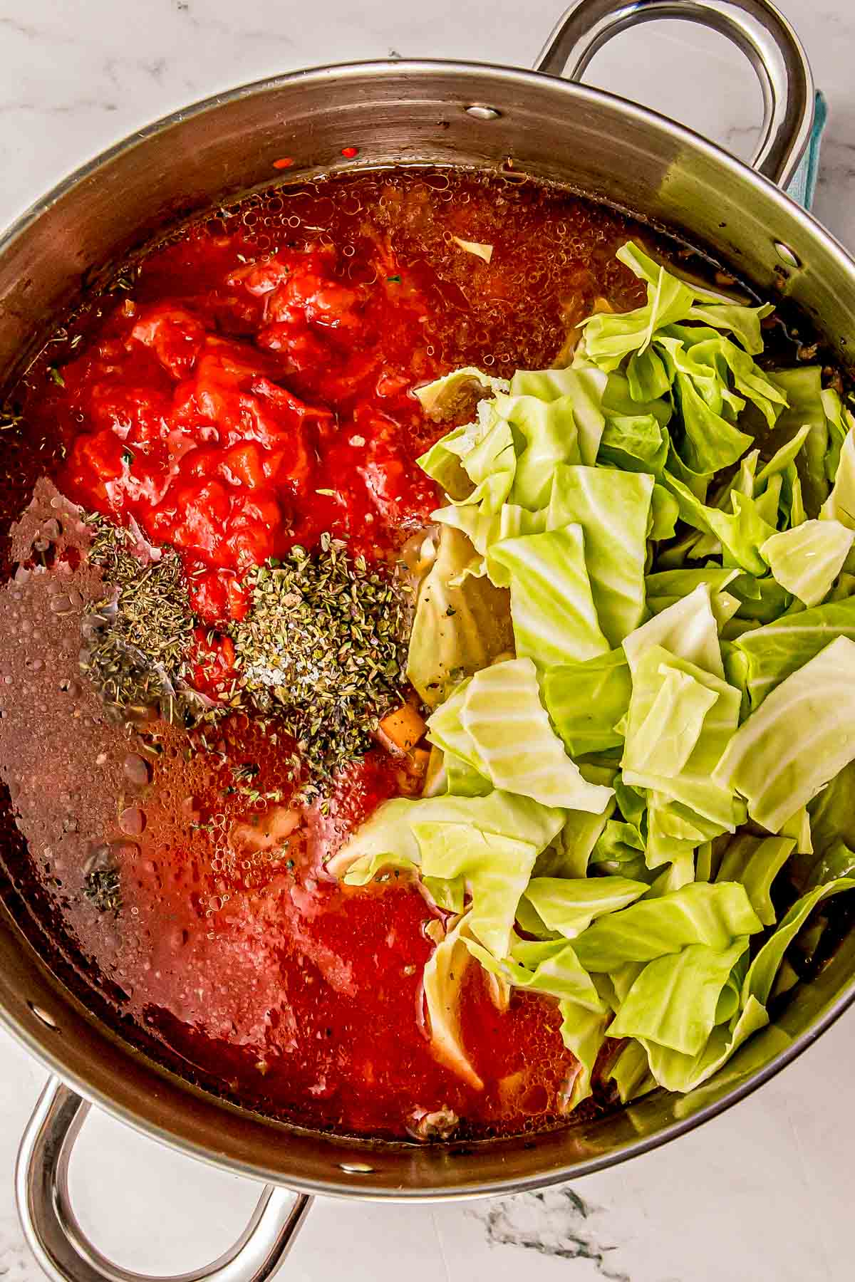 Chopped cabbage, diced tomatoes, and marinara added on top of the browned pork