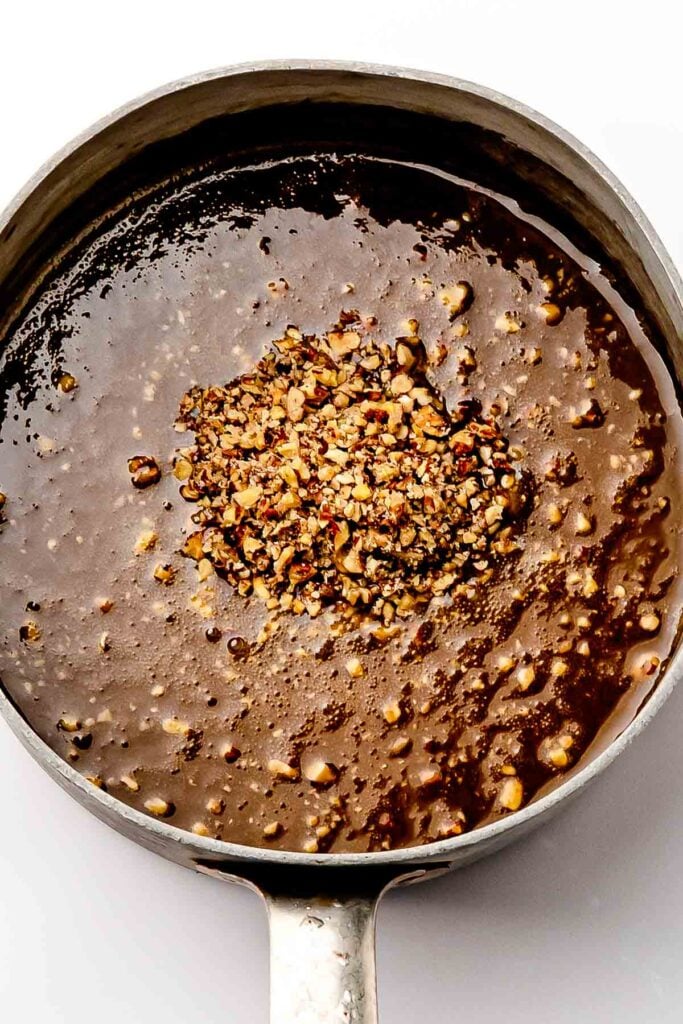 Topping cooking: Butter, maple syrup, and heavy cream bubbling in a saucepan with pecans