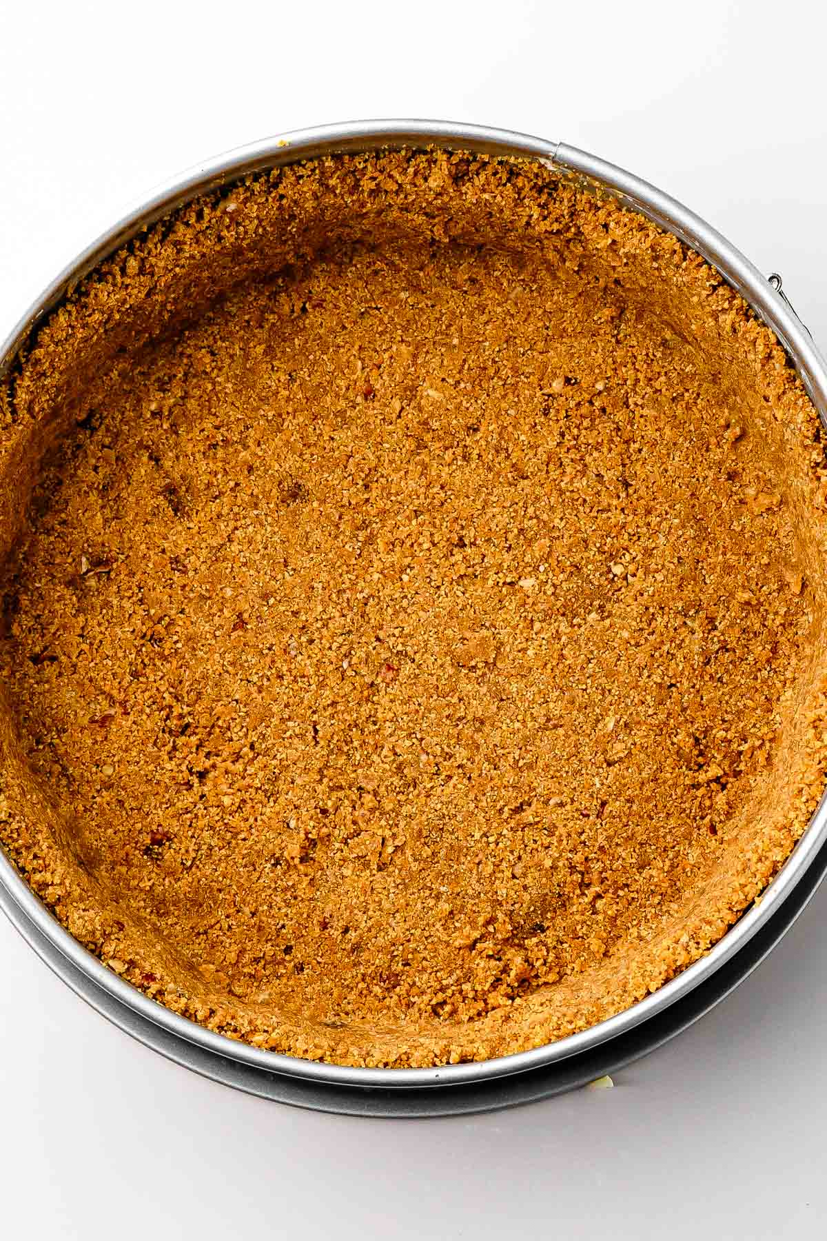 Crust pressing: Pressing the crust mixture into a springform pan with the bottom of a flat glass
