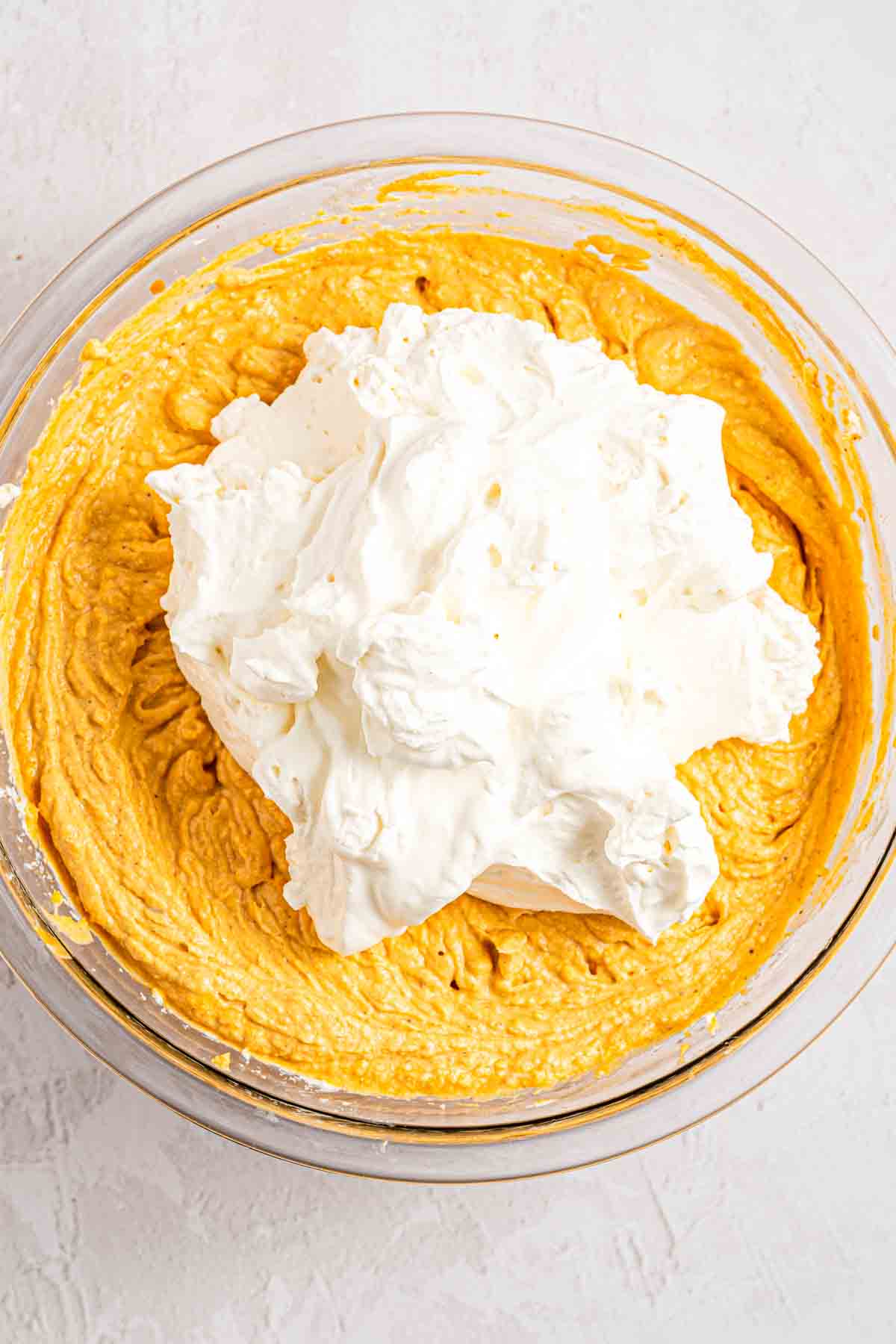 Folding whipped cream into pumpkin cheesecake filling with a spatula