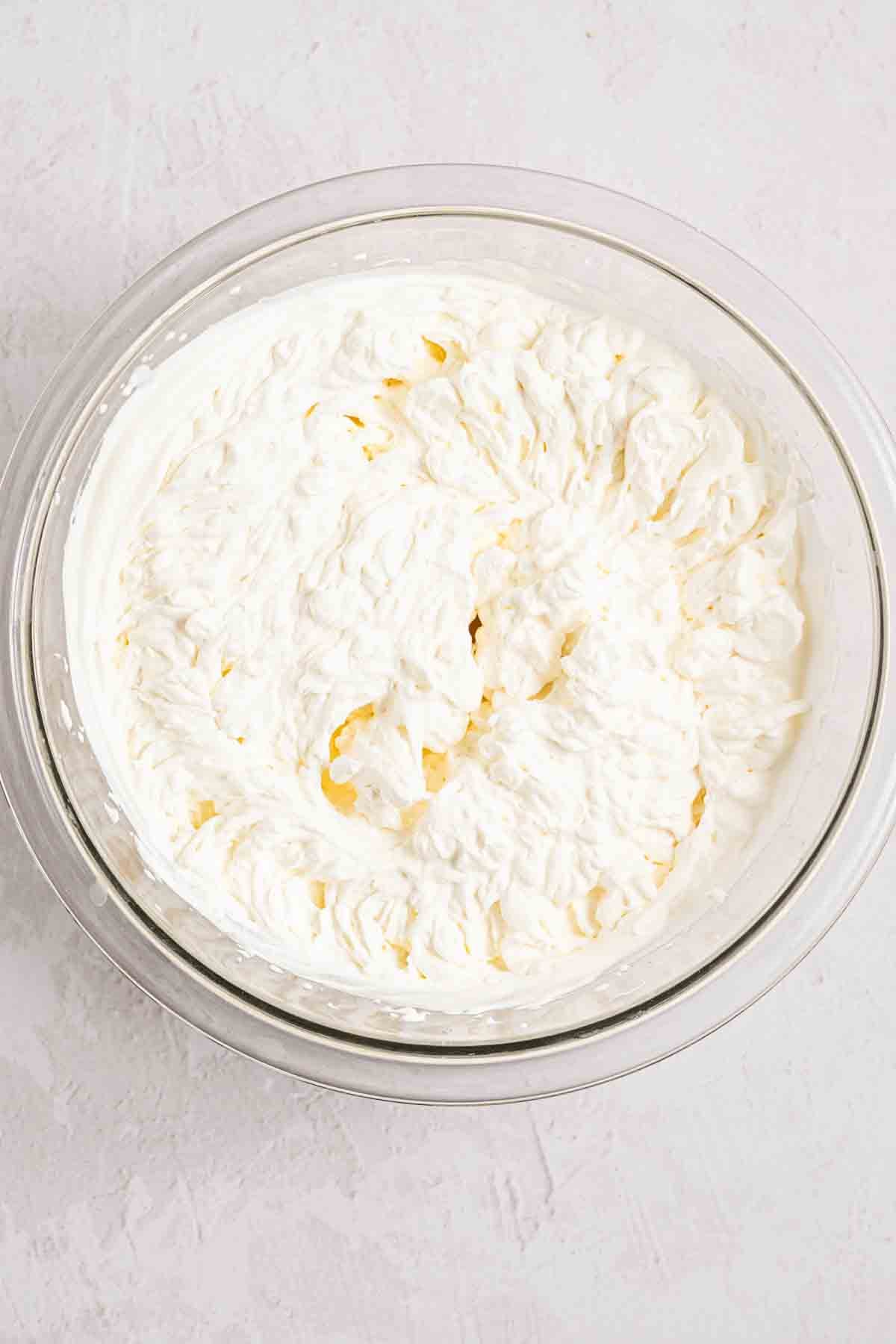 Stiff whipped cream peaks in a bowl for no-bake cheesecake filling