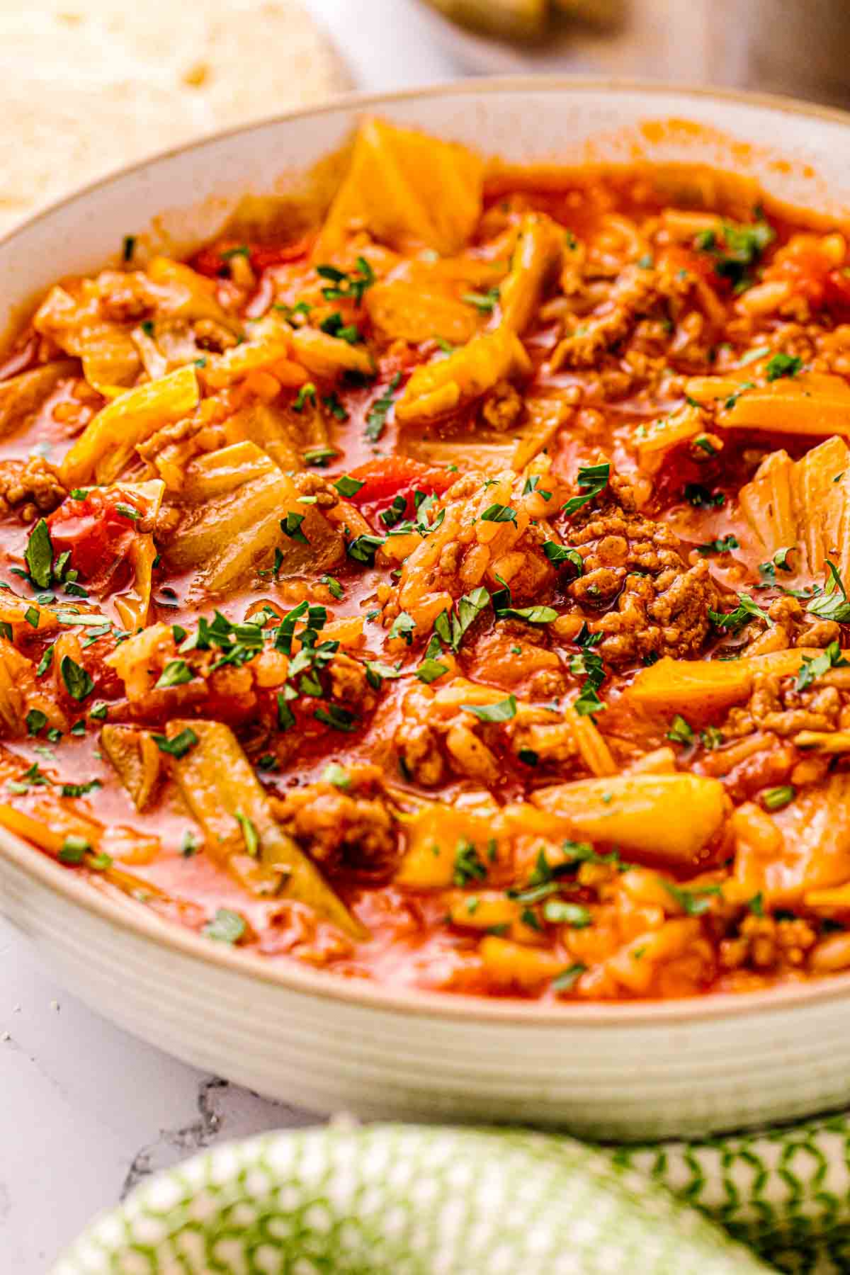Bowl of cabbage roll soup with ground pork, rice, and chopped parsley