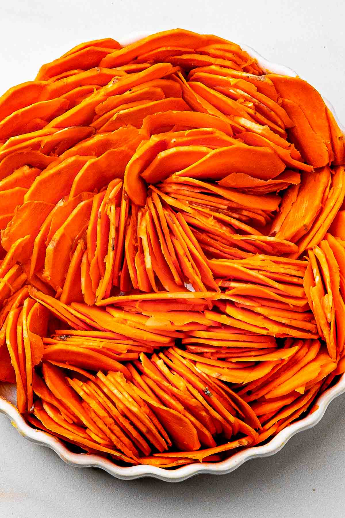 sliced raw sweet potatoes in the casserole dish