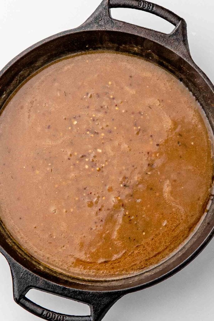 Beer, Dijon, and Worcestershire sauce simmering in the skillet with onions, ready for the chicken