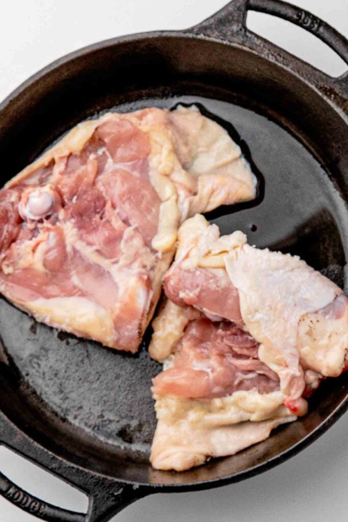 Patting bone-in, skin-on chicken thighs dry with paper towels before seasoning with salt and pepper