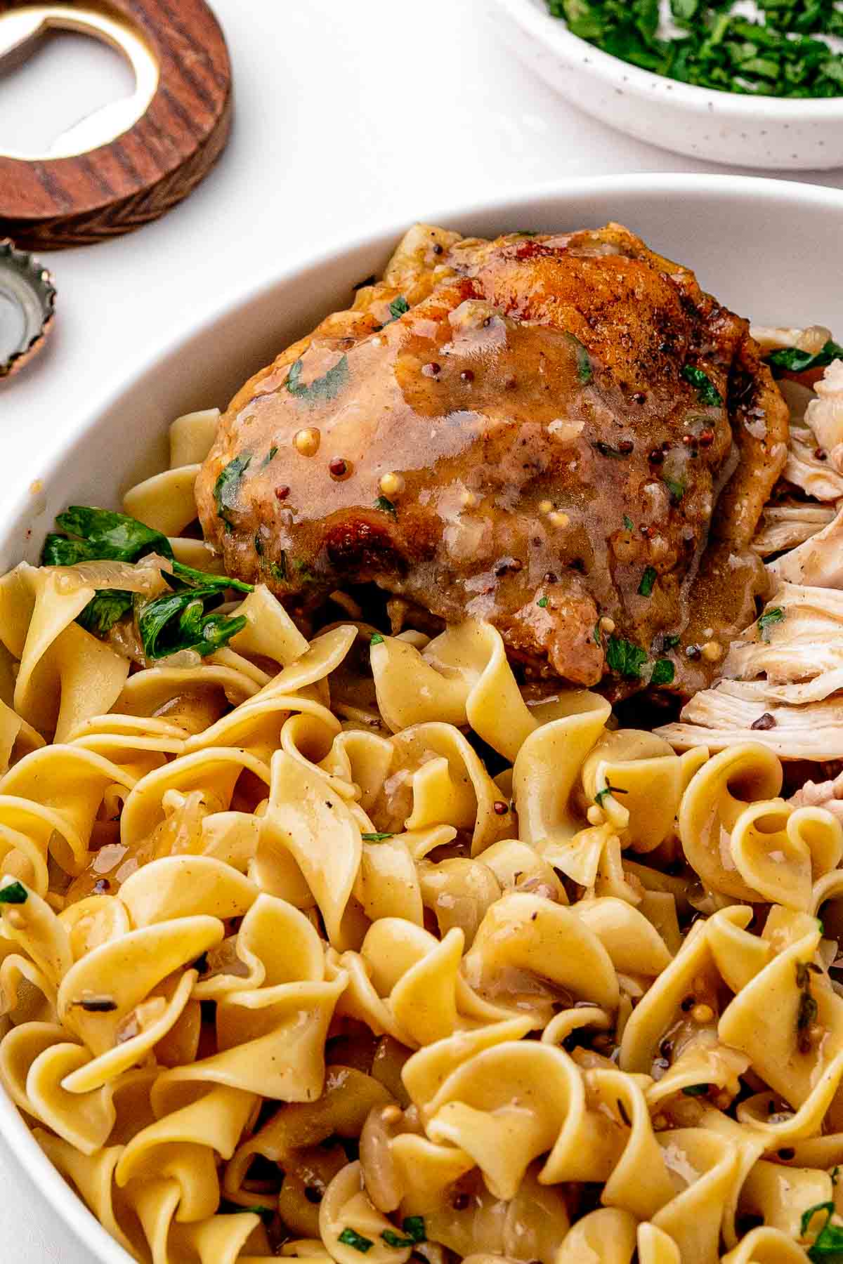 Braised chicken thigh on buttery noodles with beer sauce spooned over and fresh parsley on top