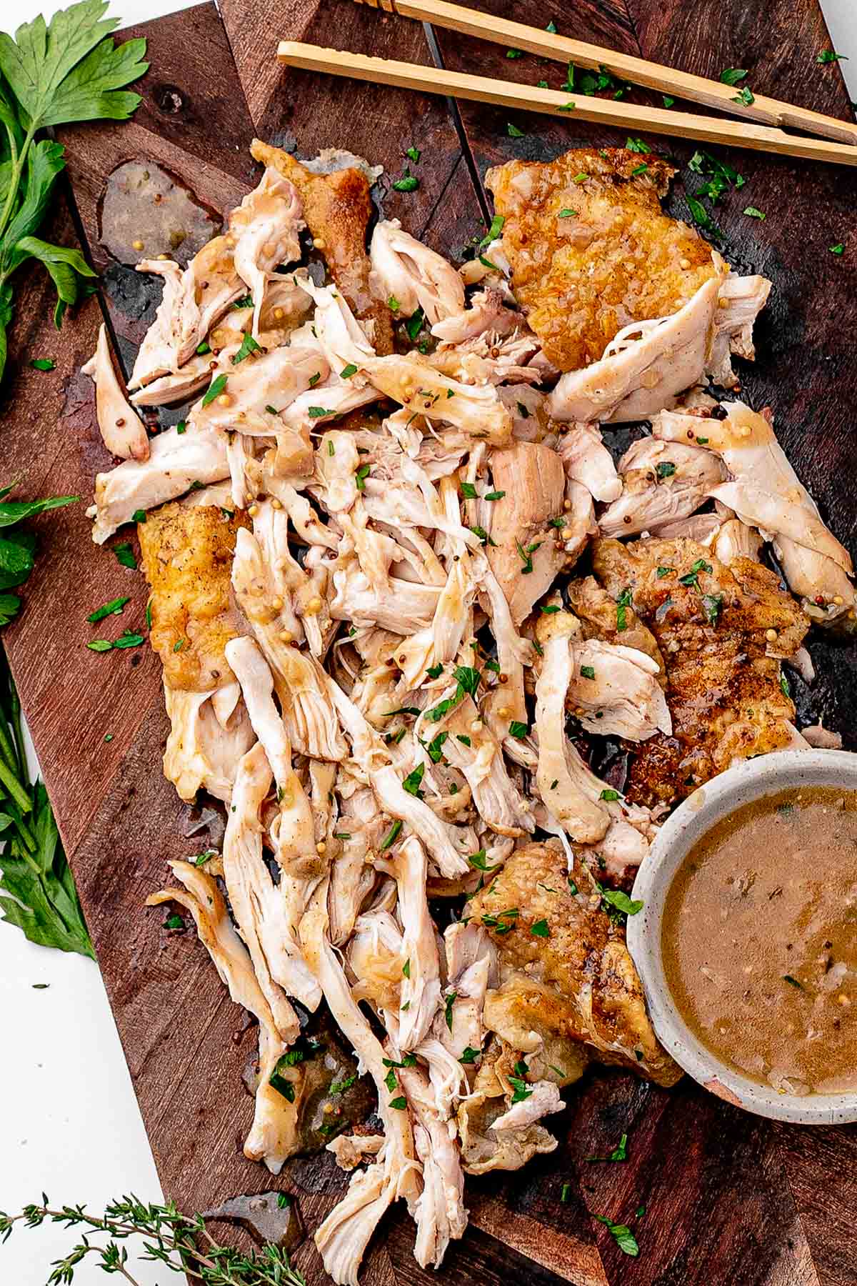 Braised chicken thigh pulled from the bone, showing juicy dark meat and crispy skin on the cutting board with beer sauce