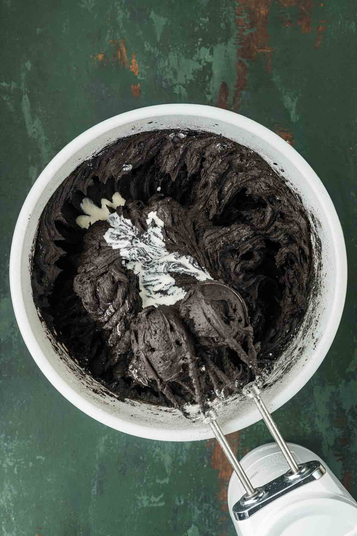Adding cocoa and sugar: Powdered sugar and black cocoa powder being beaten into butter for buttercream
