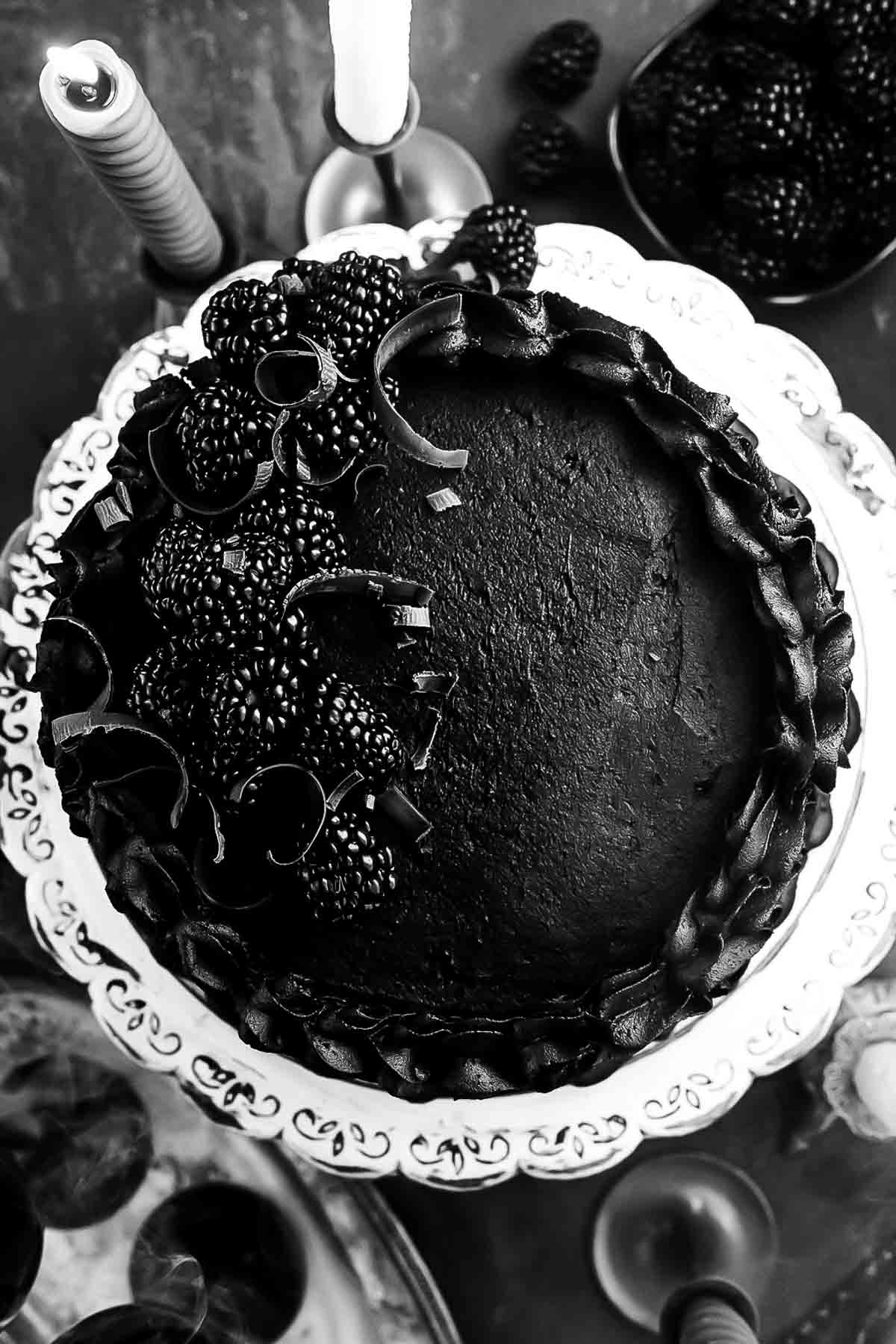 Overhead view of black velvet cake with piped buttercream swirls and blackberries