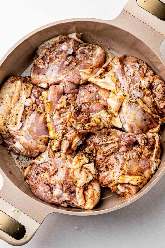 Raw dry rub chicken thighs skin-side up on a sheet pan covered in homemade lemon pepper rub