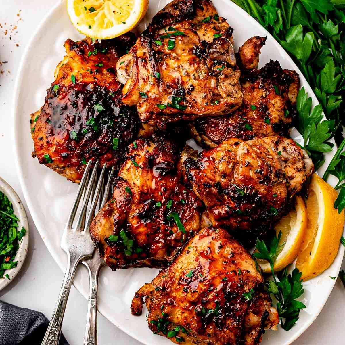 Crispy dry rub chicken thighs with homemade lemon pepper rub on a sheet pan with lemon wedges and parsley