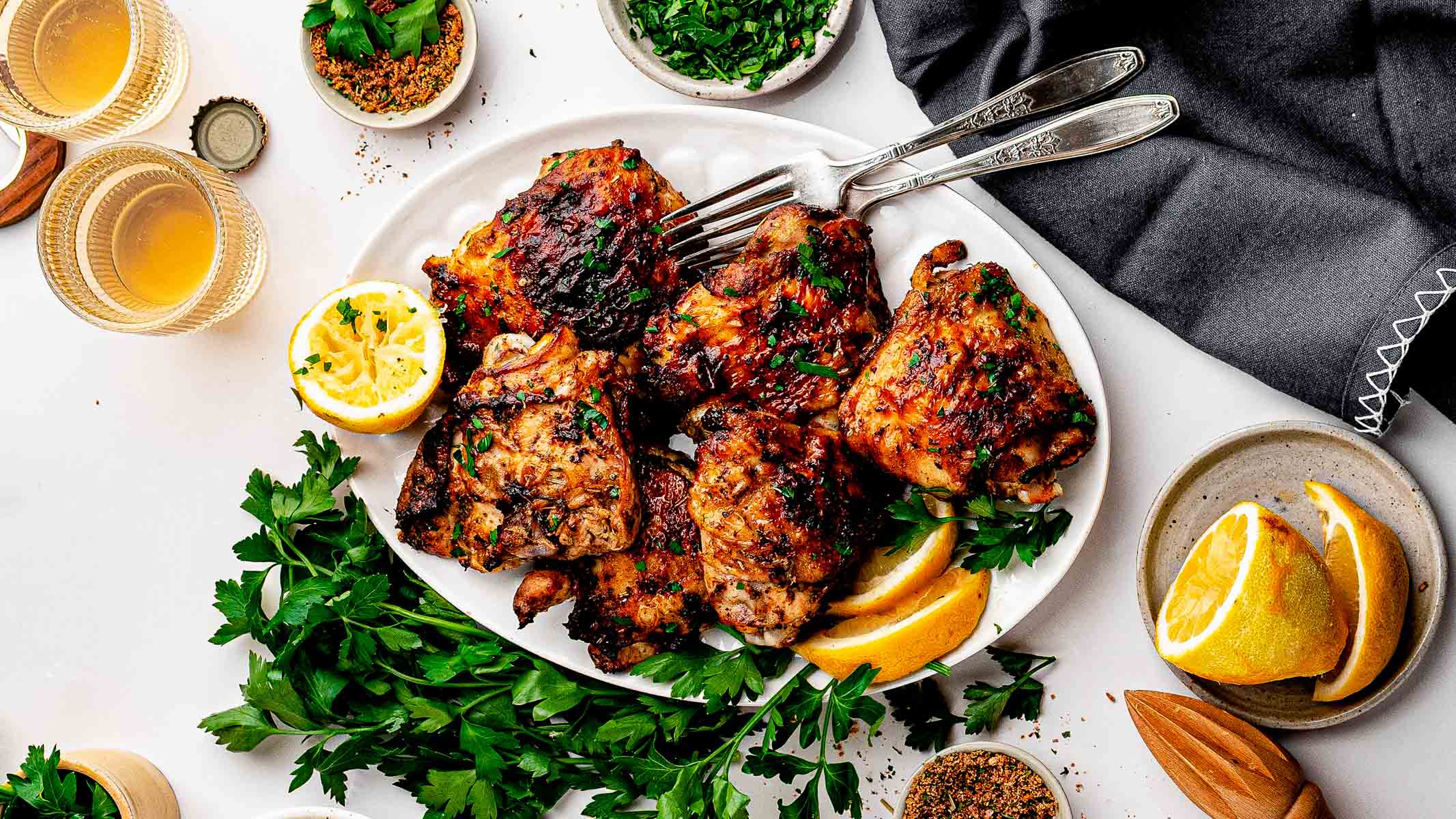 Crispy dry rub chicken thighs with homemade lemon pepper rub on a sheet pan with lemon wedges and parsley
