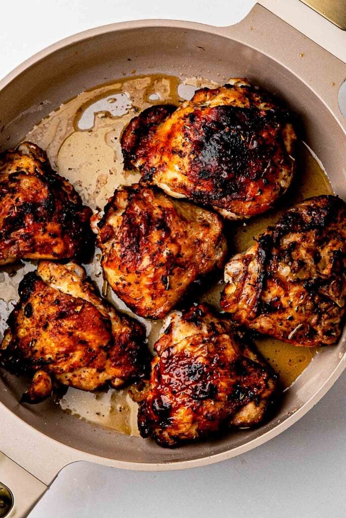 Roasted dry rub chicken thighs in a cast-iron skillet with deep golden homemade lemon pepper rub skin