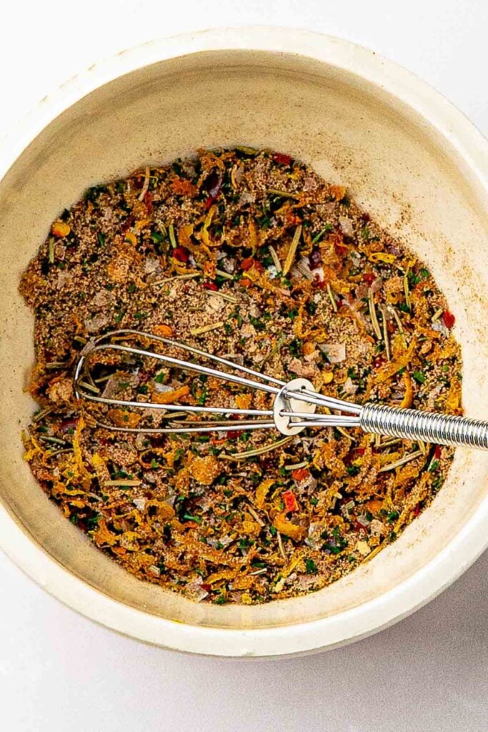 Overhead of homemade lemon pepper rub in a small bowl with yellow zest and red paprika flecks