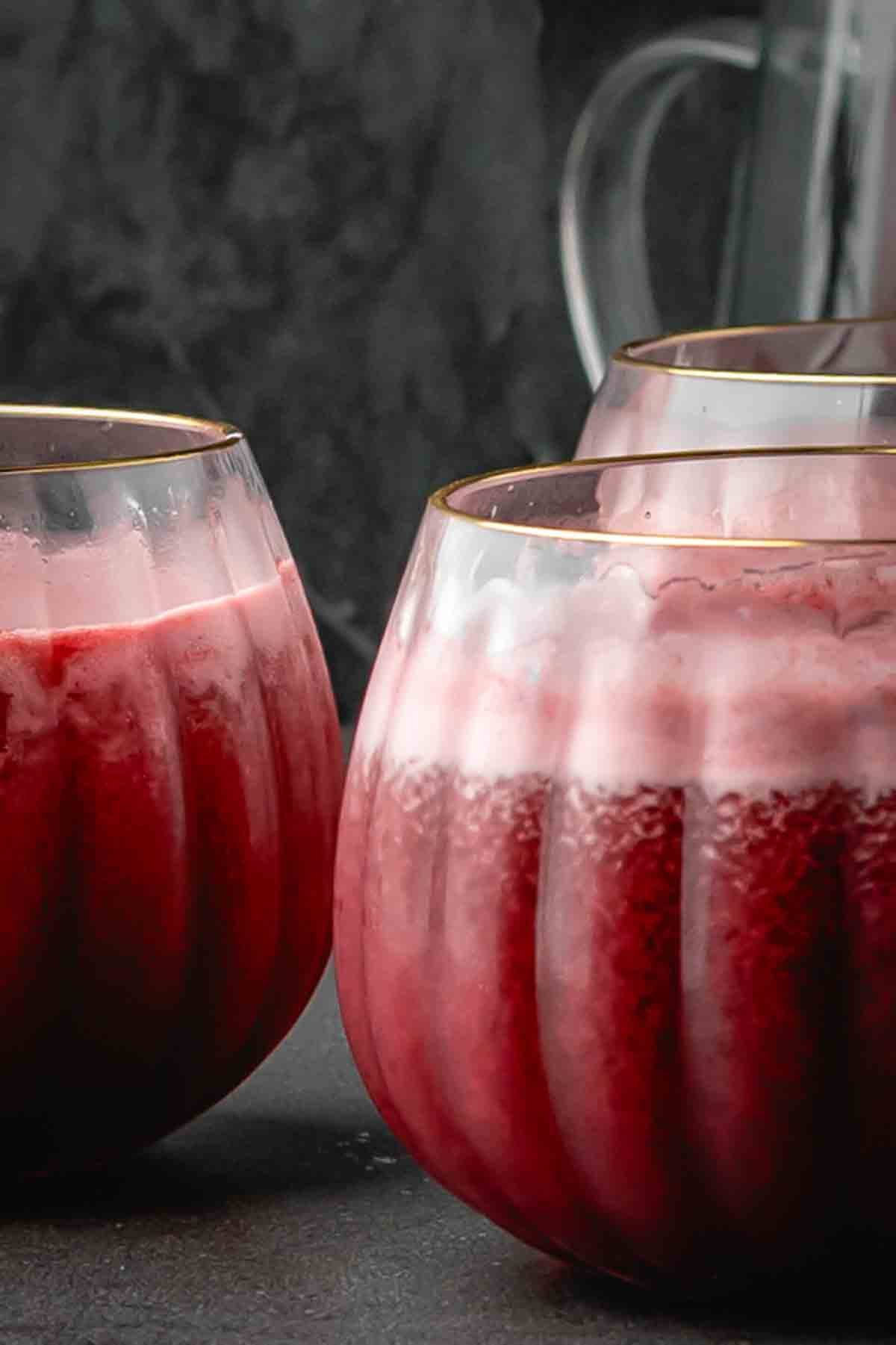 Fizzy purple Halloween mocktail in clear round glasses with golden rim